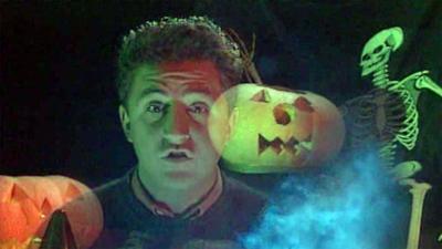 Newsround's Paul Welsh in the dark with pumpkins and skeleton