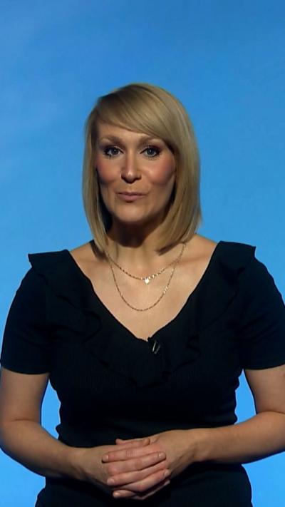 Woman in black top with hands linked in front of her in front of a blue background