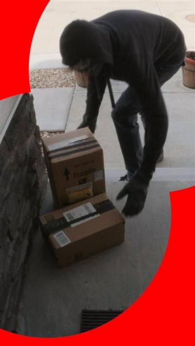 A person wearing black gloves steals parcels from a doorstep