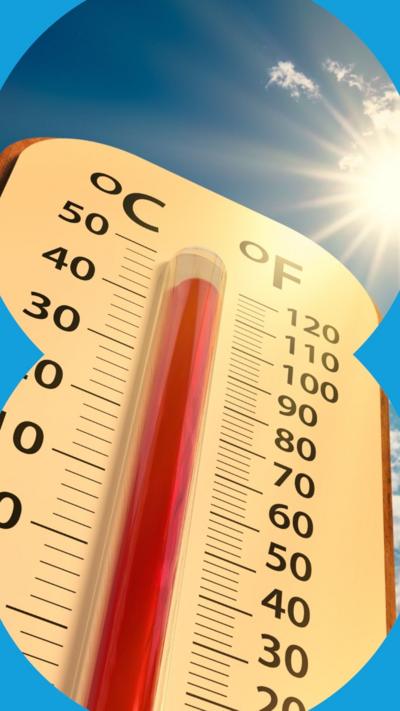 Low angle view of a thermometer against a blue sky with sun shining in the background. It shows an increased temperature of over 40 degrees celsius.