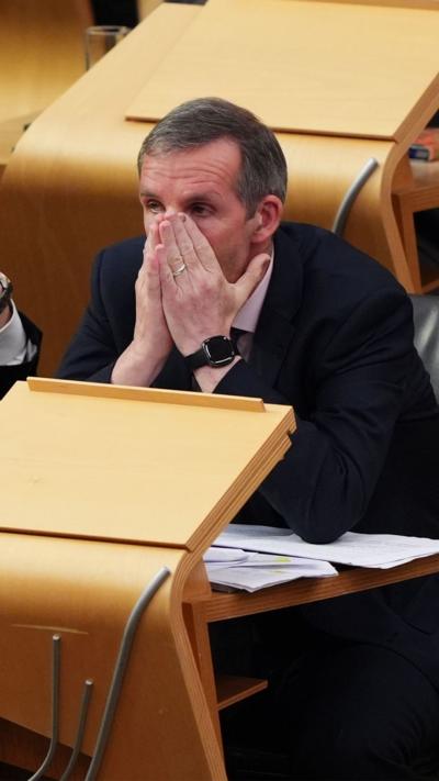 MSP Liam McArthur has his head in his hands as he finds out his bill on assisted dying has passed stage one at the Scottish Parliament.