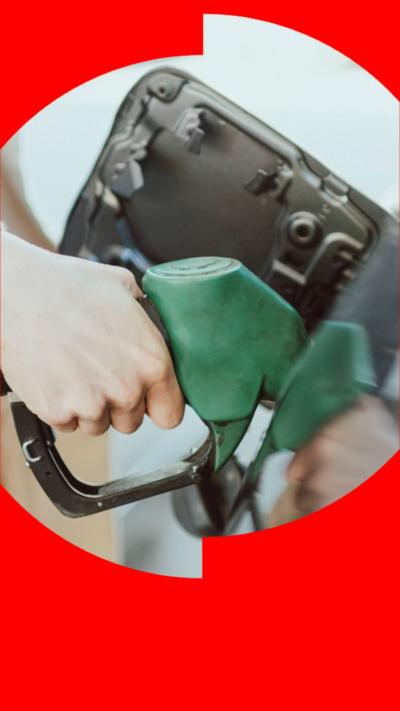 A woman's hand putting fuel in her car using a green fuel pump.
