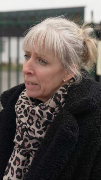 A woman with white hair looks to the left of the camera