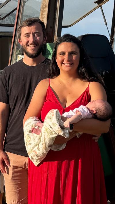 A man wearing a black t-shirt and a woman in a red dress holding a baby