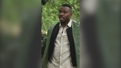 Fekky stands among trees wearing a green jacket. He has short black hair.