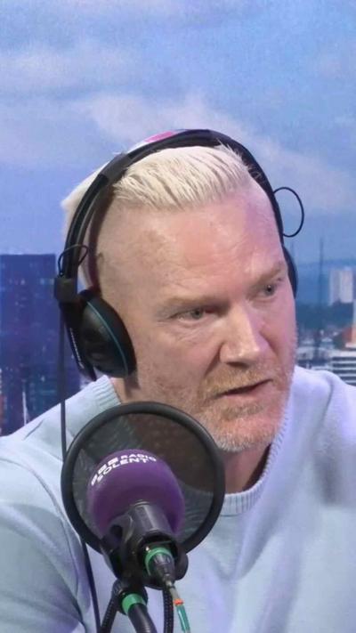Iwan Thomas sits in a radio studio wearing headphones and speaking into a microphone.