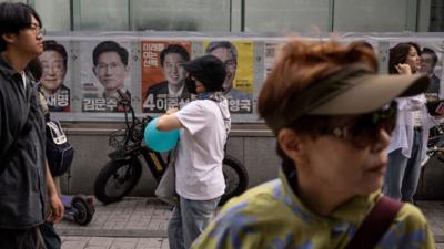 People walk past electoral posters of South Korea's presidential candidates in Seoul, South Korea.
