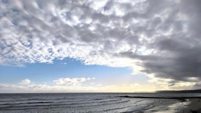 A chink of blue sky with grey clouds rolling in over the coast 