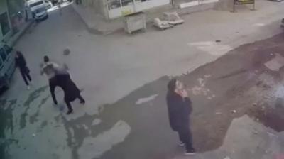 People look around in street as masonry falls to the ground