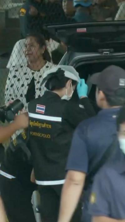 A person in blue scrubs puts on PPE from the trunk of a vehicle.