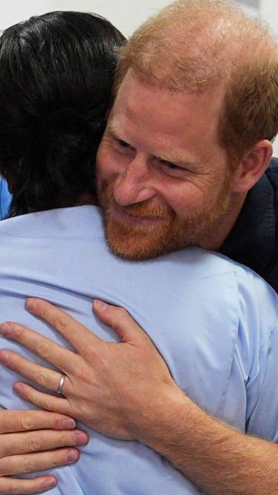 Prince Harry hugging a nurse in a blue top