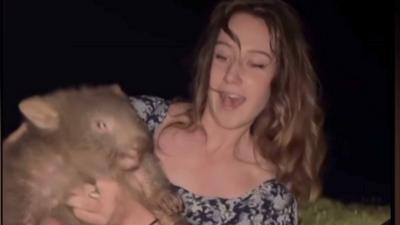 Woman in sundress holding baby wombat 