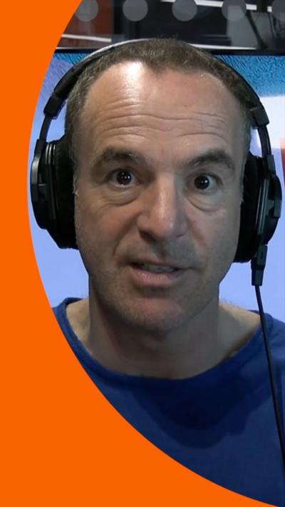 Martin Lewis looking at the camera, wearing headphones and a blue top