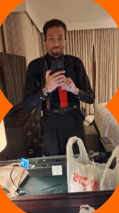 Cole Tomas Allen in a selfie taken in a mirror. He's wearing a black shirt and trousers and a red tie. Reuters