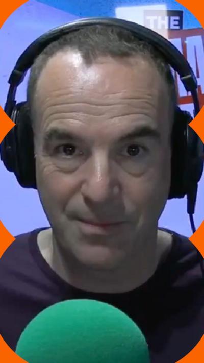 A man wearing headphones looks at the camera, sat in front of a green mic.