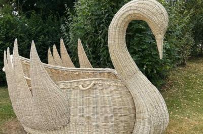 A willow swan made by craftspeople. It is placed on a green lawn