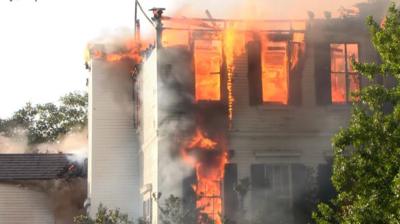 A white building with fire emerging from inside 