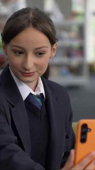 Girl in school uniform smiles at mobile phone