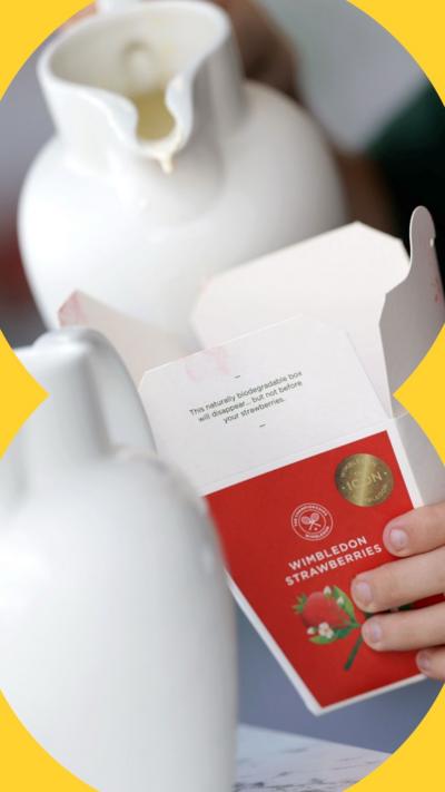 Cream being poured into a box of strawberries