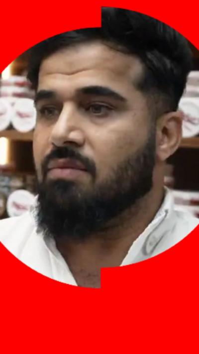 A man with dark hair, full beard and moustache, wearing a white shirt.