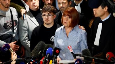 Gisèle Pelicot speaking outside court surrounded by onlookers 