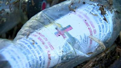 Plastic bottle with dirt and grass on it with Bible verse inside