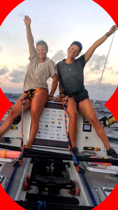 Two women pose for a celebratory photo on board their boat on the Pacific Ocean