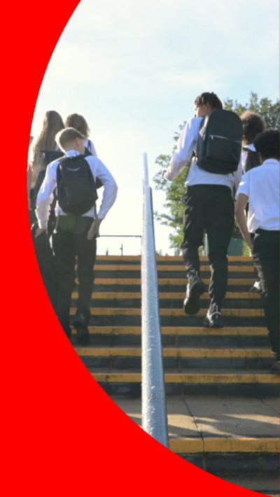 Boys in white shirts and black trousers walking up steps either side of a handrail.
© Getty Images