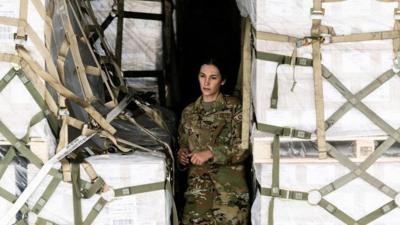 An airman in the cargo bay of a plane carrying baby formula