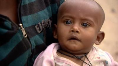 A baby waiting in line for food