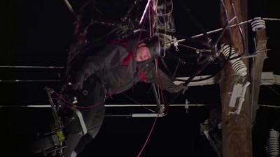 Paraglider hanging face down from power lines