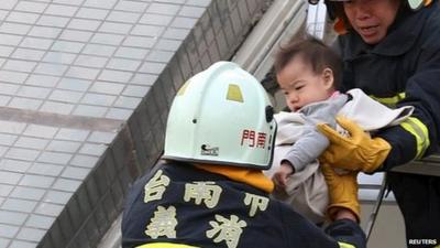 Rescue workers remove a baby from the site where a 17-storey apartment building collapsed after an earthquake hit Tainan,