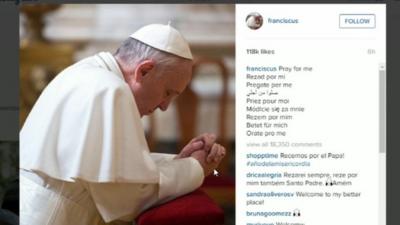 Pope Francis kneeling with his head bowed in prayer. The accompanying caption reads "Pray for me" and is repeated in eight other languages.