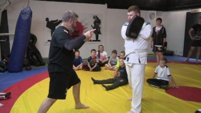 Local martial arts coach Danny Corr demonstrates new techniques to young children