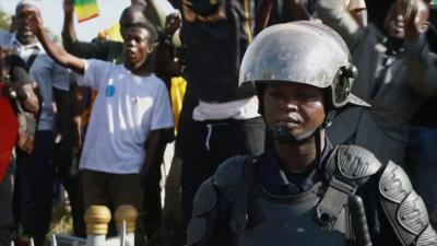 Scene from Bamako as people celebrate, while a police officer watches