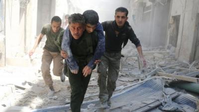 Syrians move an injured man amid the rubble of destroyed buildings following a reported air strike in Aleppo