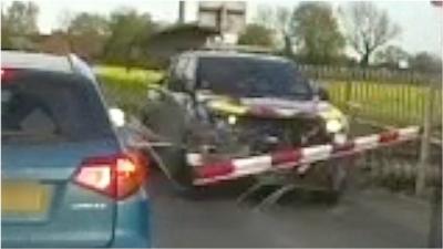 Car crashes through barrier at level crossing.