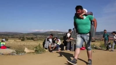 Asylum seeker carrying his elderly mother on his back in Macedonia