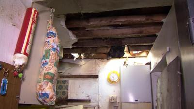 A ceiling with a large hole in a dirty room