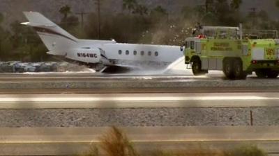 Plane on tarmac after skidding to a stop. Fire crews suppress any potential fire.