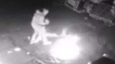 The man is seen pouring liquid on a door of a disused farm before being engulfed in a fireball.