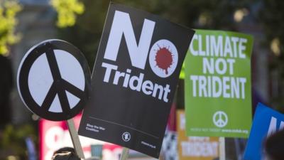 Protesters hold up placards as they demonstrate against the renewal of Britain"s Trident nuclear weapons system