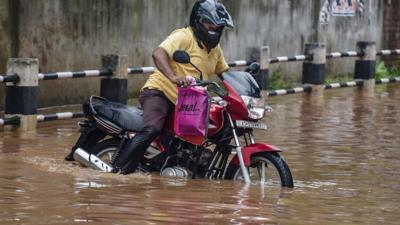 Man navigating through a flooded street on his motorbike