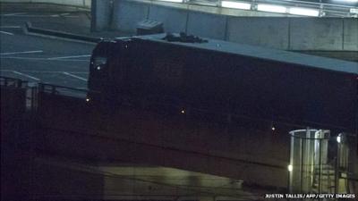 Two migrants cling to the roof of a freight truck as they arrive at the Eurotunnel terminal in the English city of Folkestone