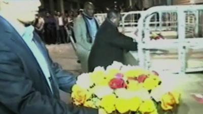 Flowers being laid on top of coffins.