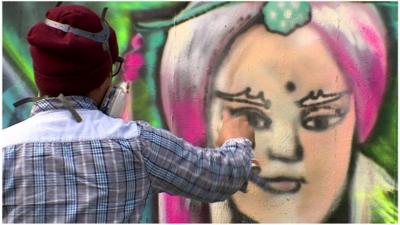 Artist sprays graffiti on a wall