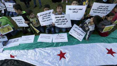 Children carry placards as they call for the lifting of the siege off Madaya and Zabadani in Syria