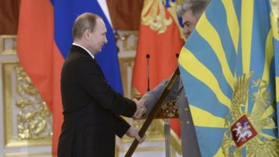 Russian President Putin hands over a flag to a returning serviceman