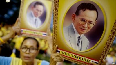 Thai well-wishers sing while holding up portraits of Thai King Bhumibol Adulyadej