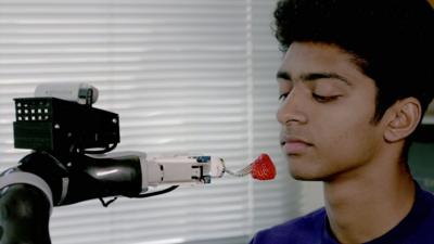 A man being fed a strawberry by the University of Washington's ADA robot